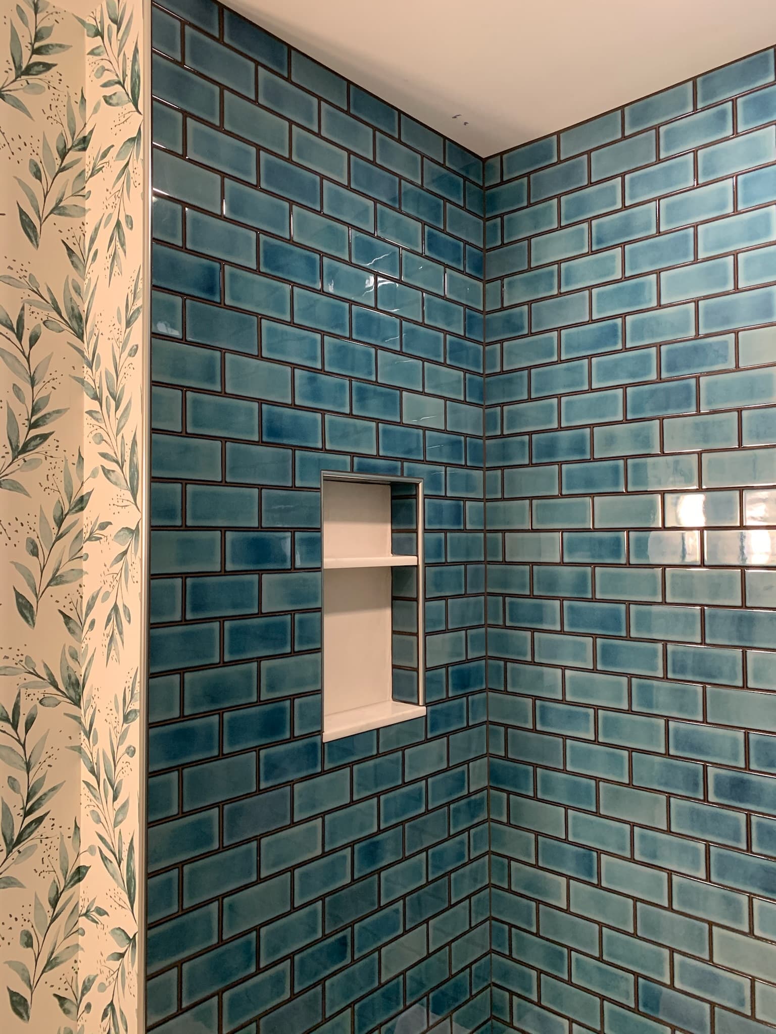 blue bathroom tile with floral wallpaper close up
